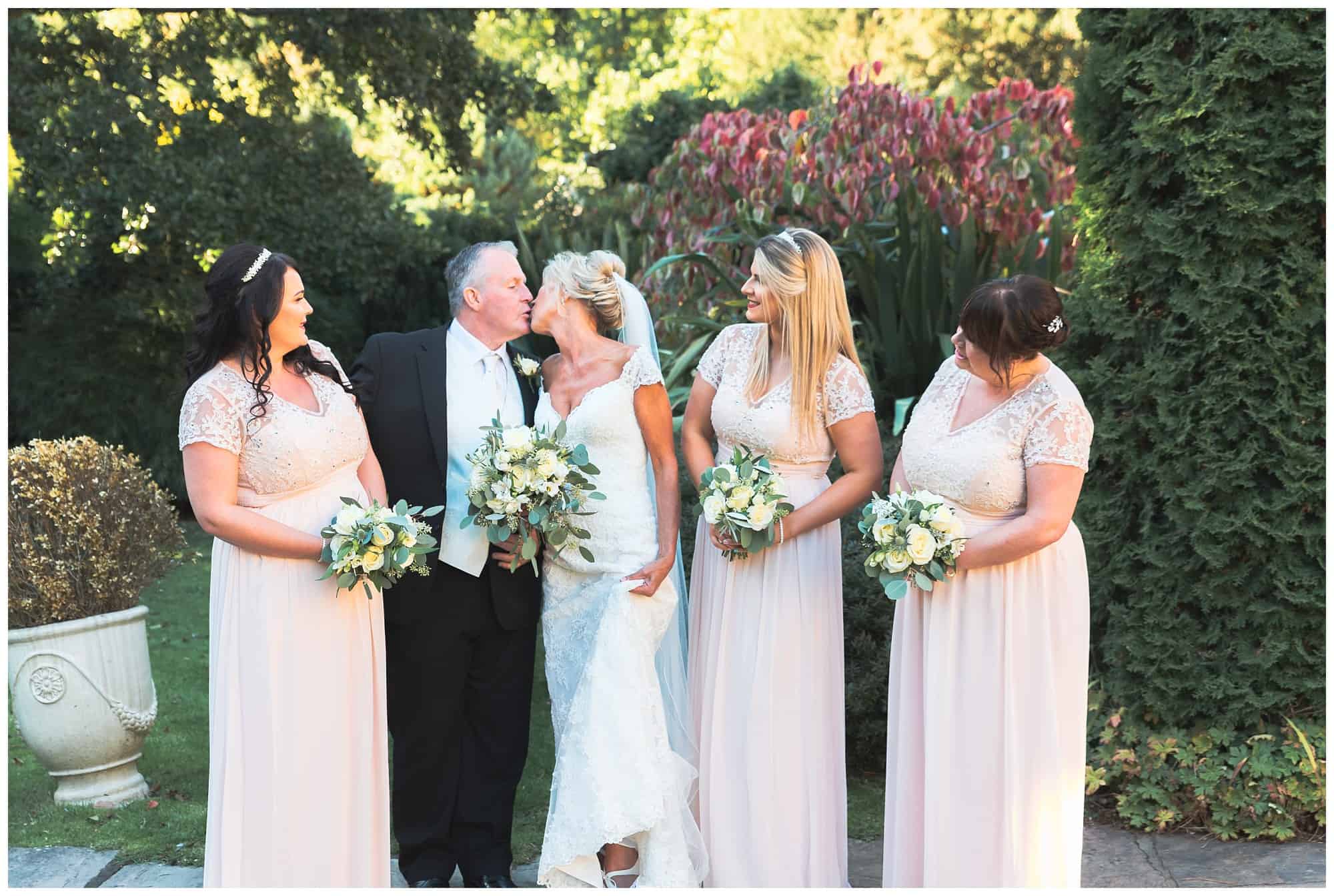 Whitley Hall Hotel Wedding - outside bride and groom kissing with bridesmaids looking speechless