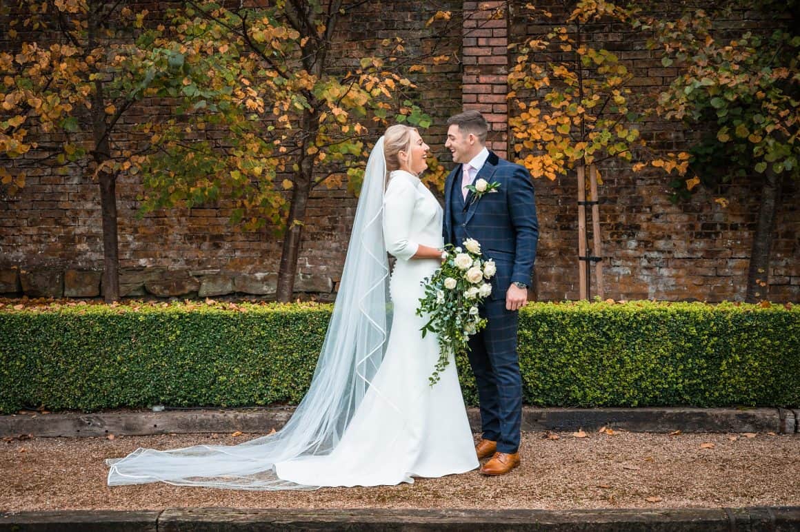 Bride and Groom posing, behind autumn trees