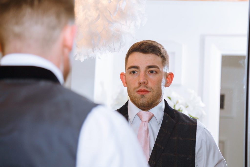 photo of groom looking in a mirror