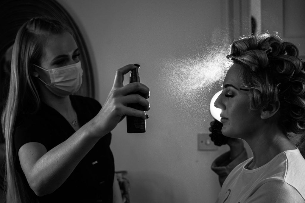 This image shows a flash photography image of a bride getting her hair sprayed light from behind