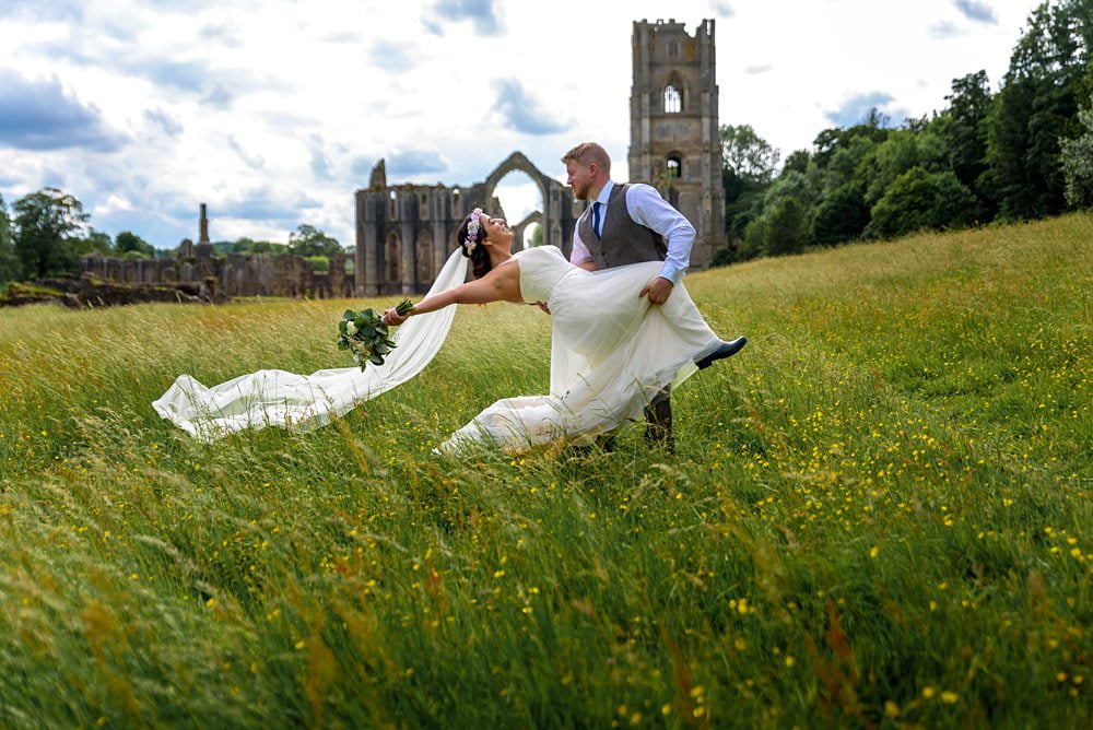 Bride and Groom pose with abbey in background photograph Fountains Abbey Rippon, Fountains Abbey Rippon Photos, Fountains Abbey Wedding photographer