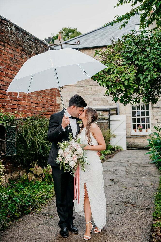 photograph of bride and groom posing with umbrella in garden, Tadcaster Rustic Yurt Wedding, Rustic Yurt Wedding Photos, Tadcaster Wedding Photographer