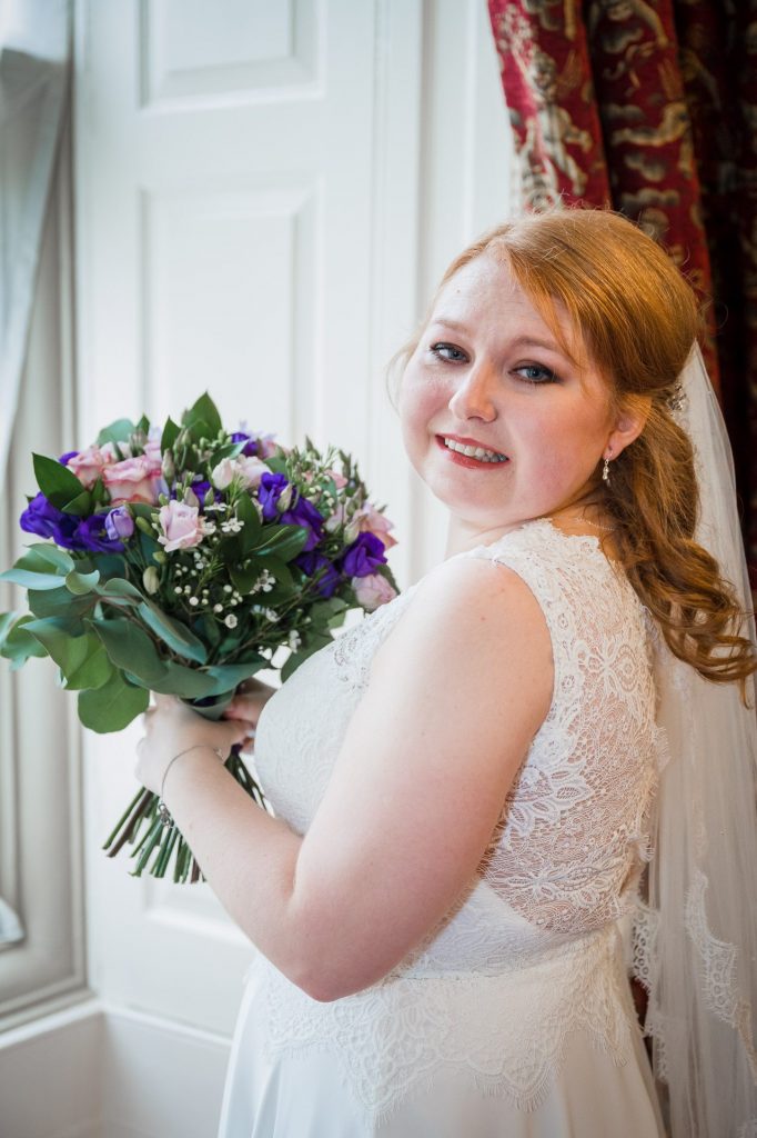 bride holiding flowers next to large window