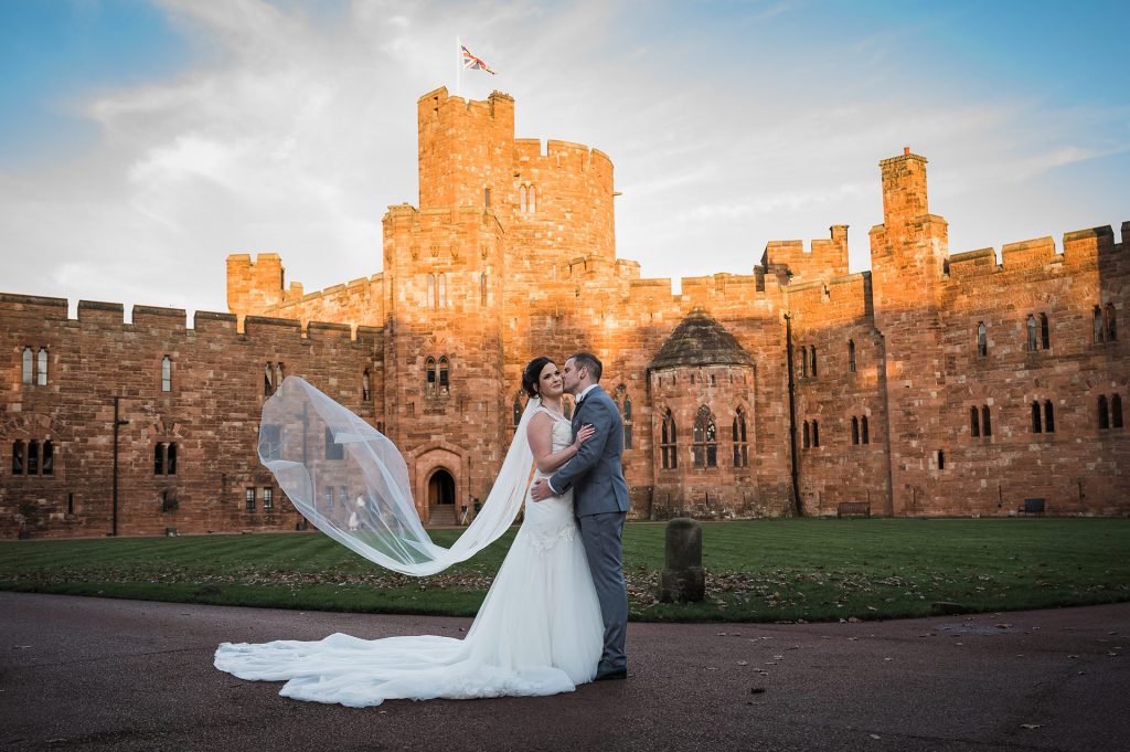 Photo of Bride and Groom walk posing in front of the castle