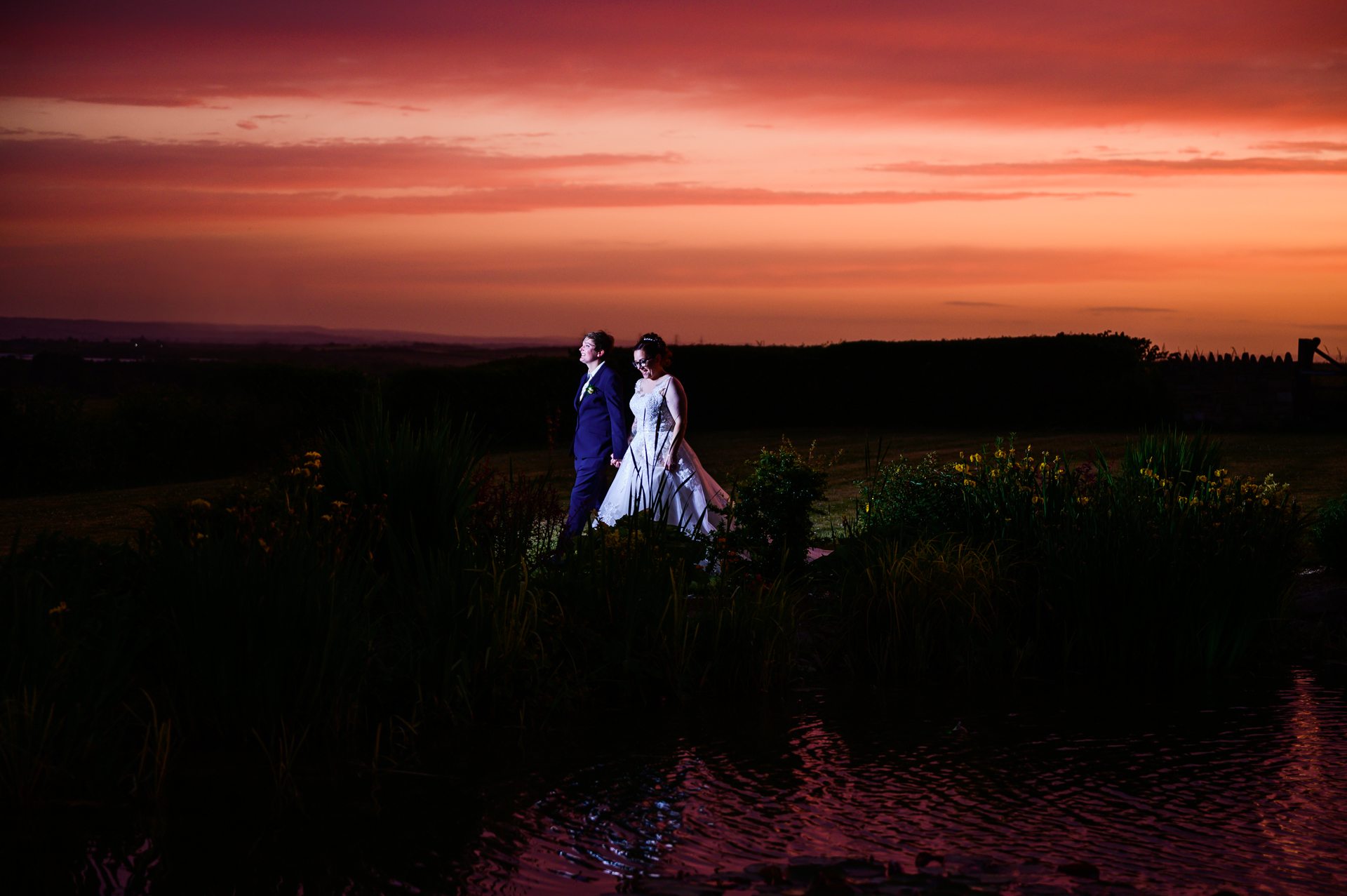bride and bride walking with sunset behind them