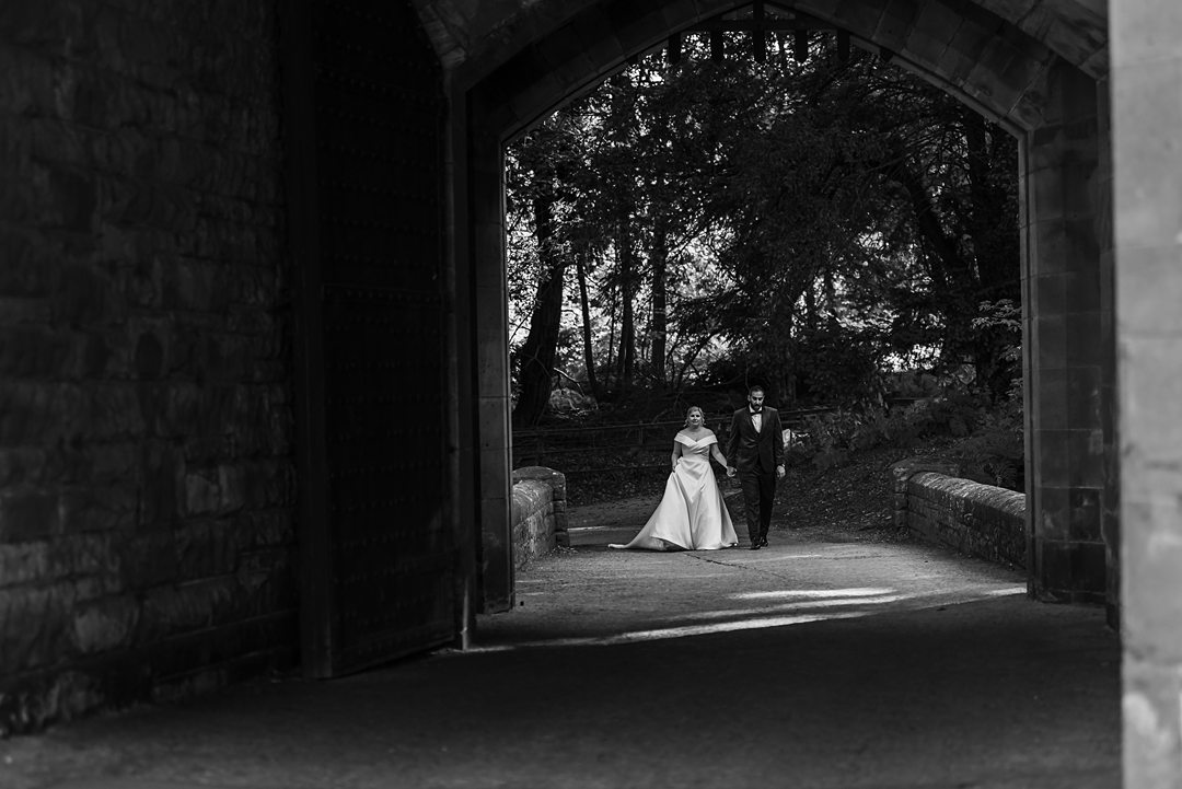 bride and groom walking through castle gates