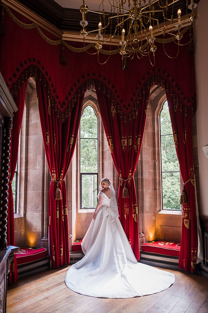 bride again posing in peckforton castle window