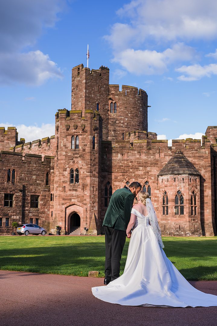 bride and groom posing with castle tower behind them