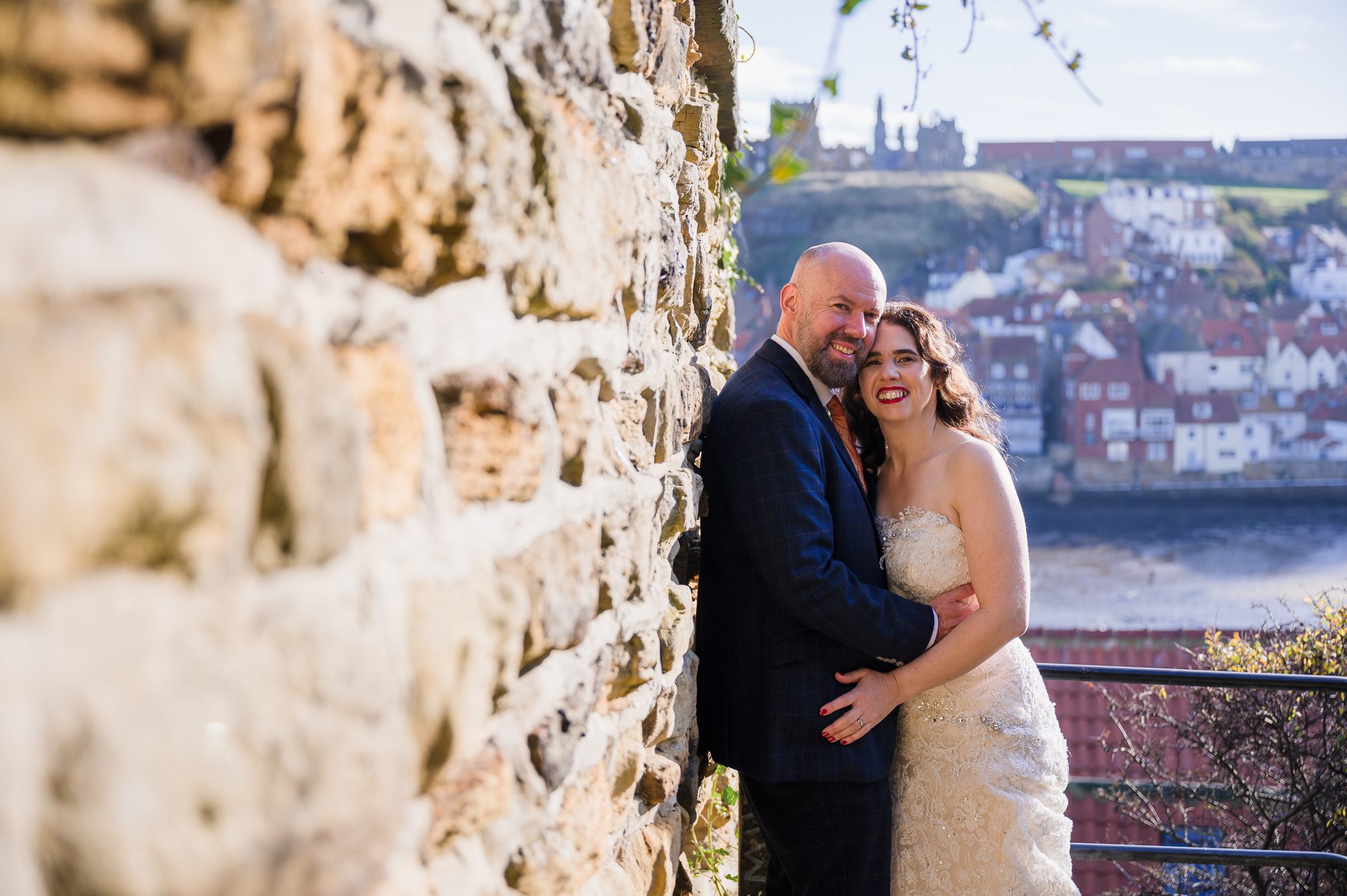 bride and groom, posing with Whitby abbey behind them