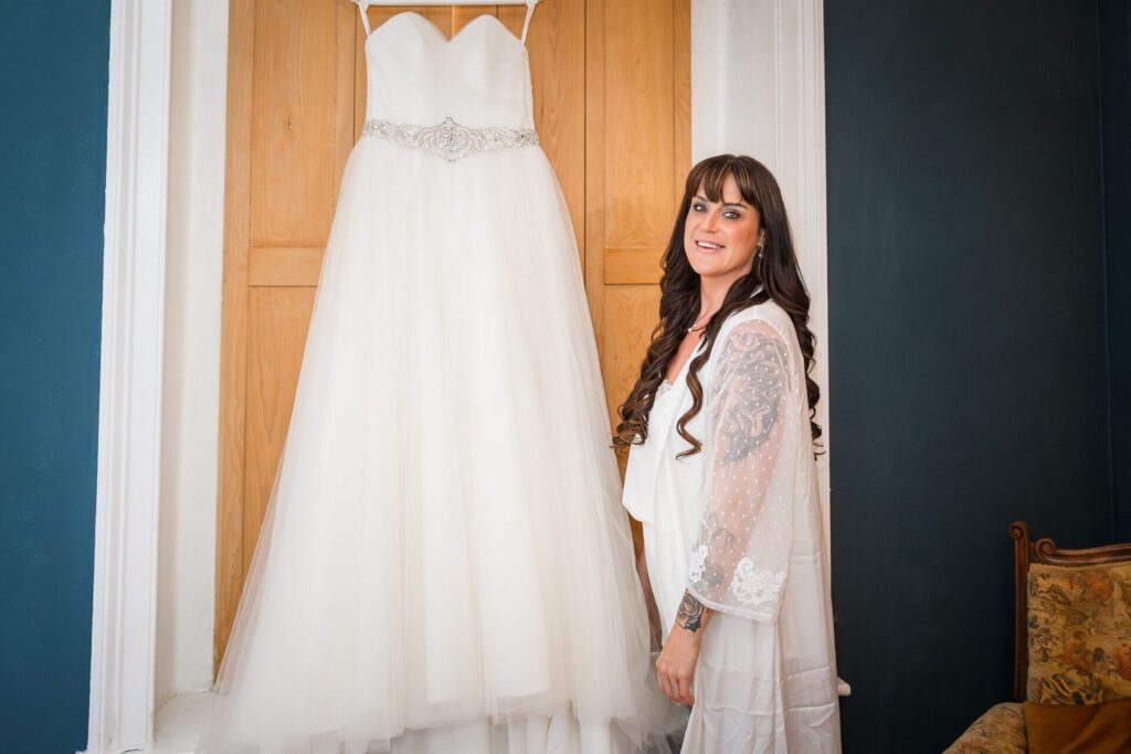 Bride smiles next to her elegant wedding dress, Whitby elopement, romantic mood