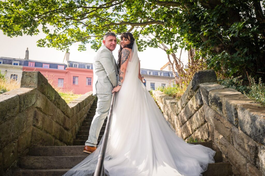 Romantic Whitby elopement: bride & groom on stone steps, colourful buildings, natural light.