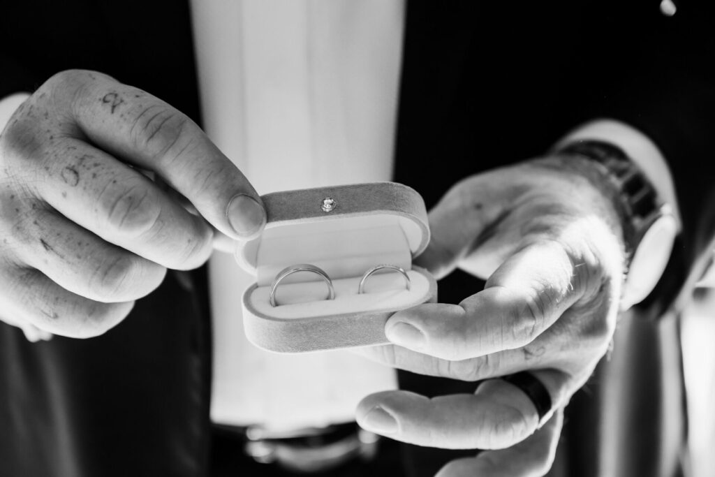 Close-up of wedding rings in a velvet box, held by hands, luxury Yorkshire wedding photography.